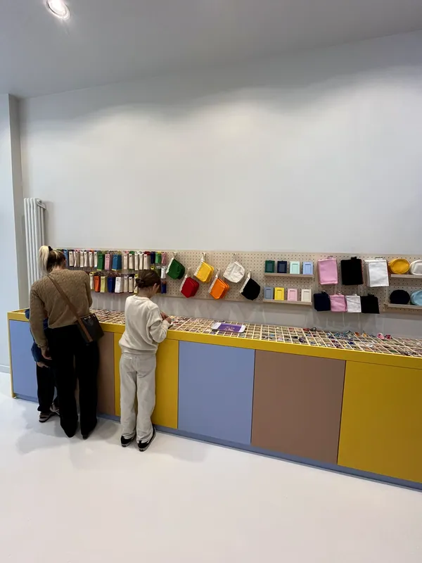 Vue de la boutique : le grand comptoir jaune, lilas et terracotta et le mur d'accessoires