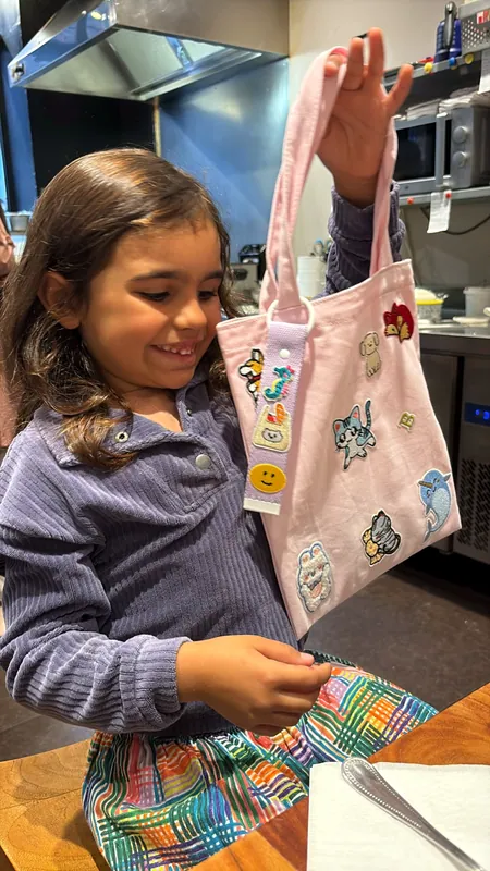 Une petite cliente montre fièrement son tote bag rose couvert d'écussons