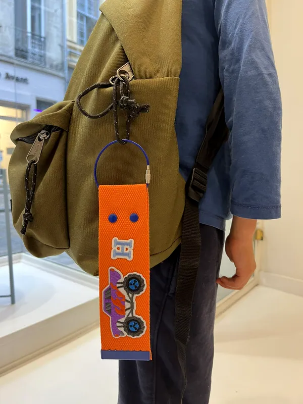 Porte-clés orange à écussons accroché à un sac à dos