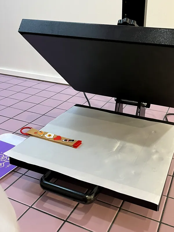 Un porte-clés personnalisé posé sur la presse à chaud, prêt à être thermocollé